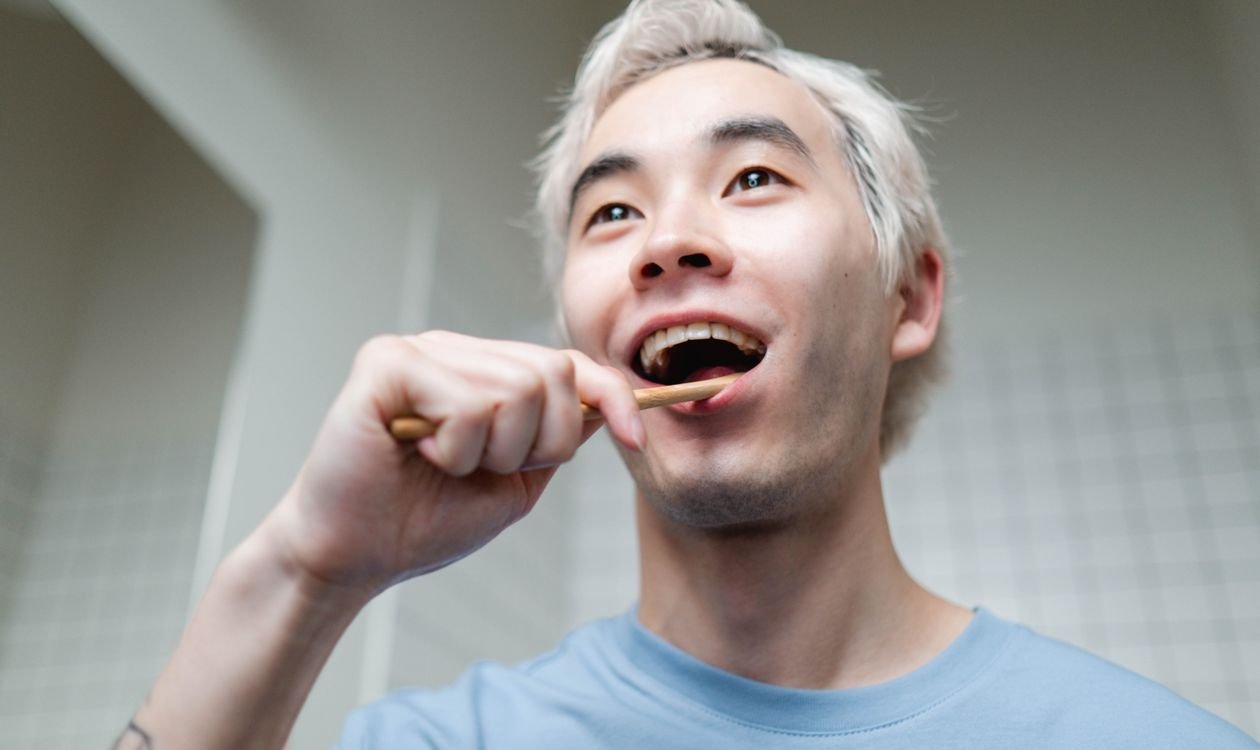 Man brushing his teeth in the bathroom as part of an oral hygiene routine